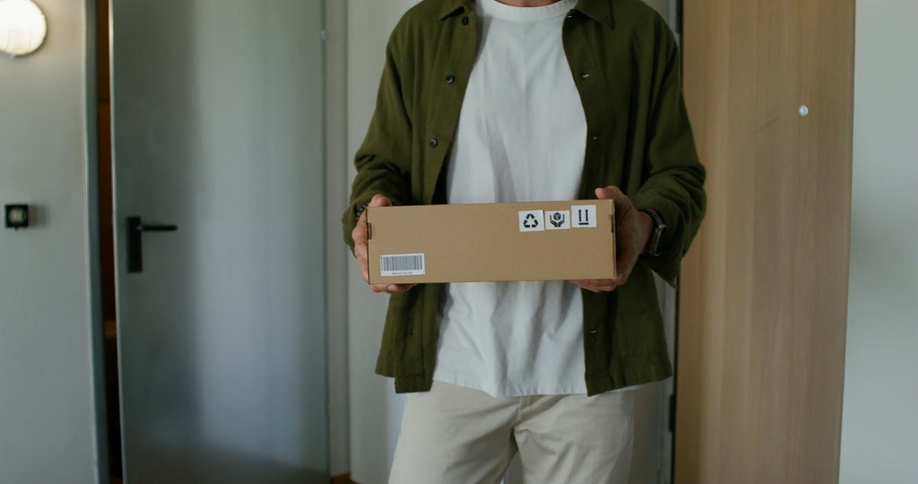 Person holding a neatly packed parcel ready for shipping inside a home or small office environment