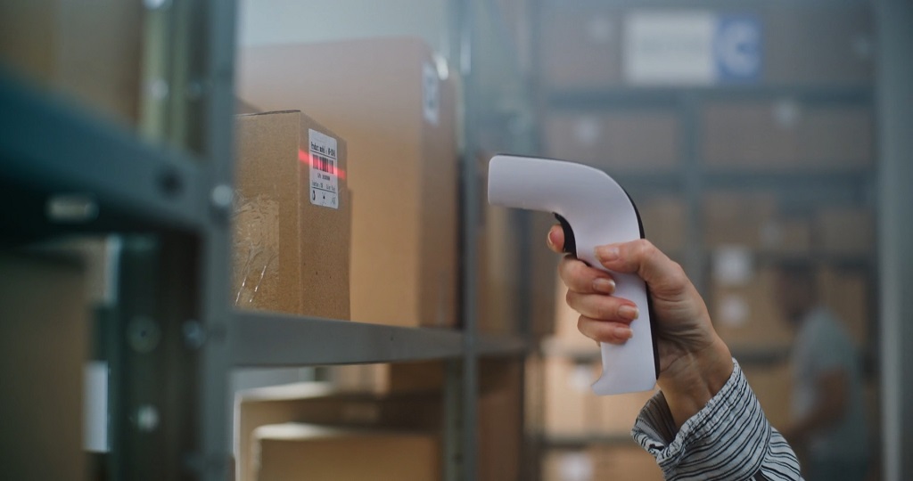 Close-up of a hand scanning a barcode label on a cardboard box in a fulfillment center